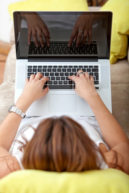 Woman lying on the couch using a laptop
